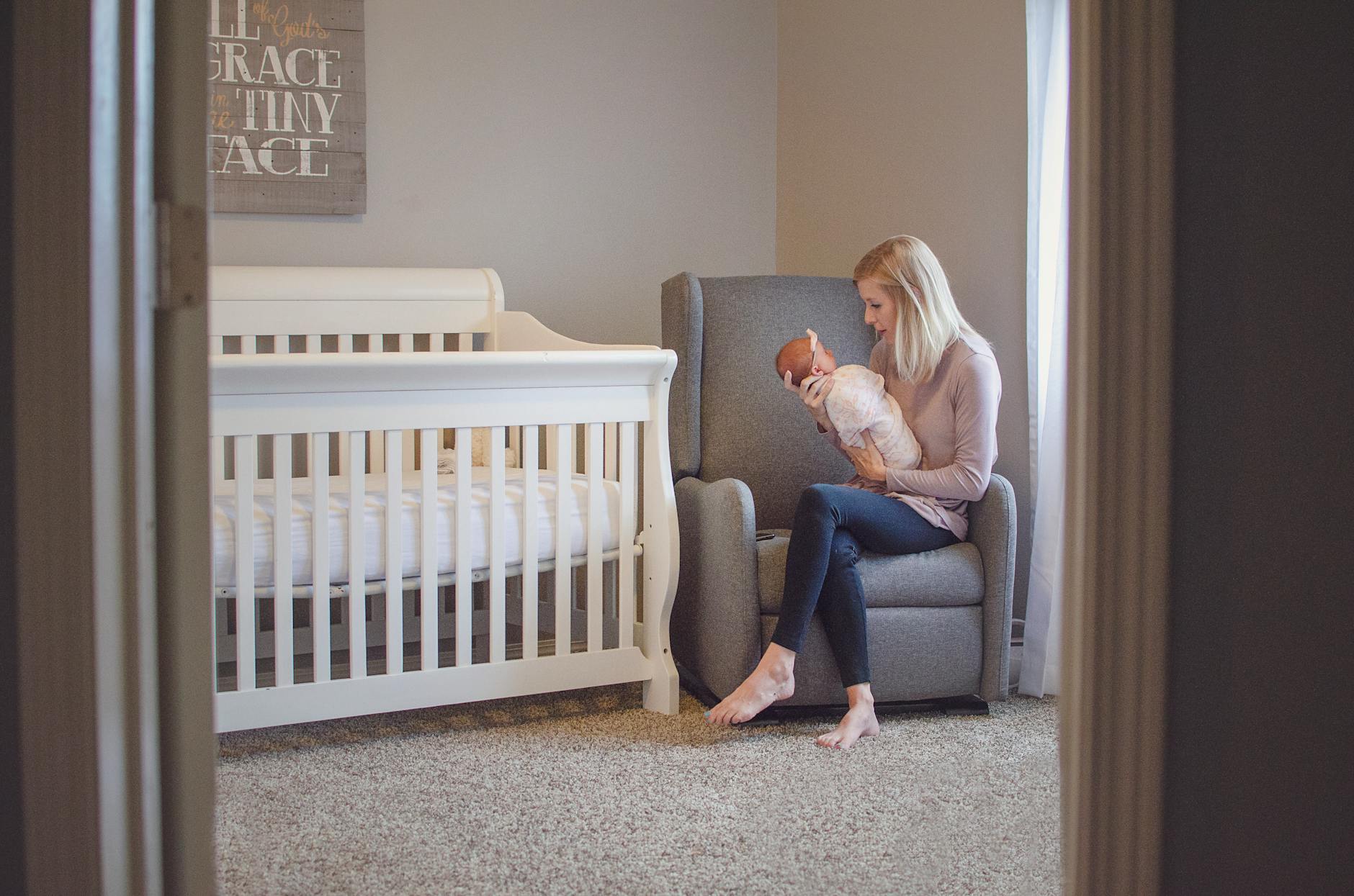 parent holding baby in cozy nursery armchair with warm table lamp glow
