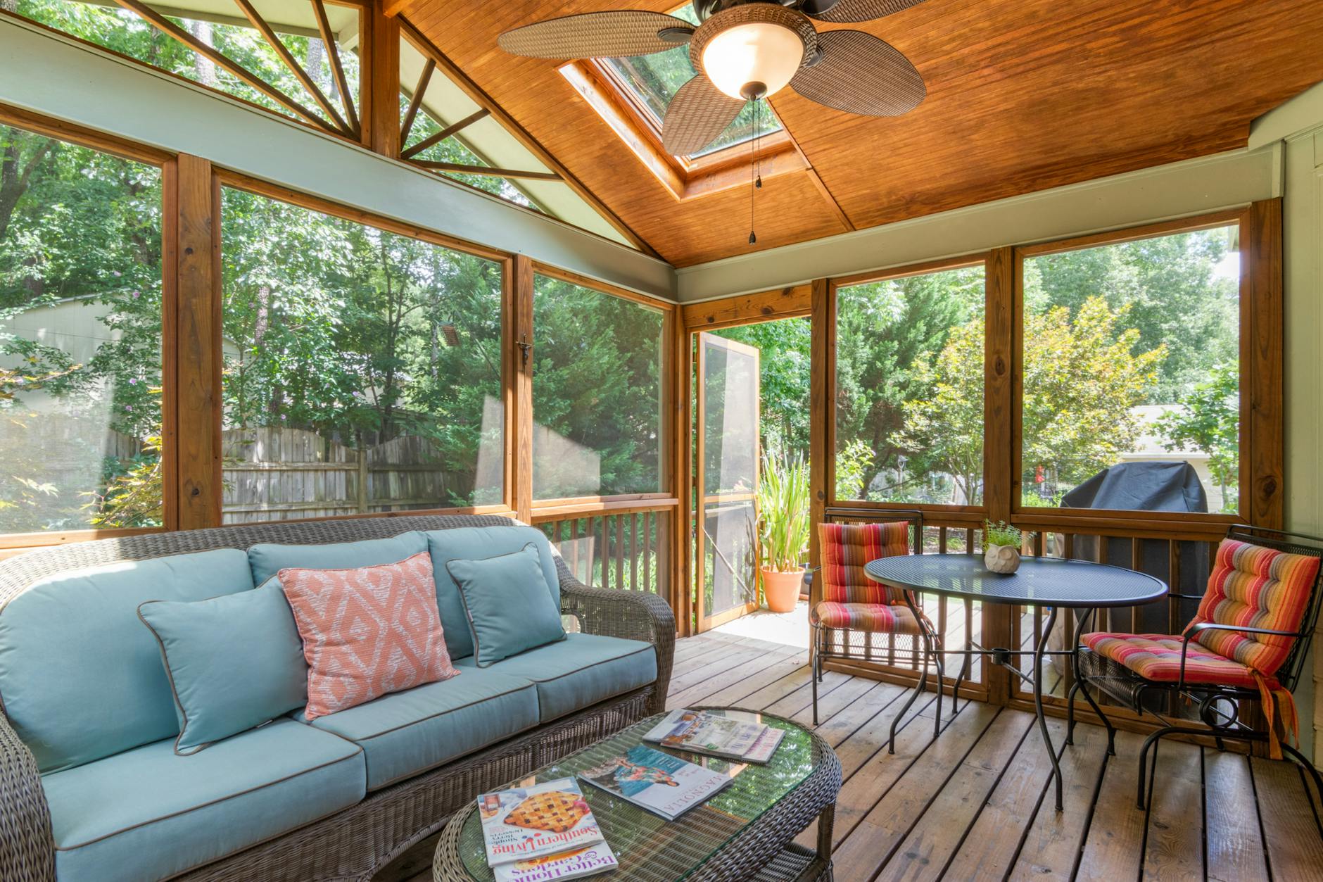A bright sunroom with wicker furniture and lush indoor plants.
